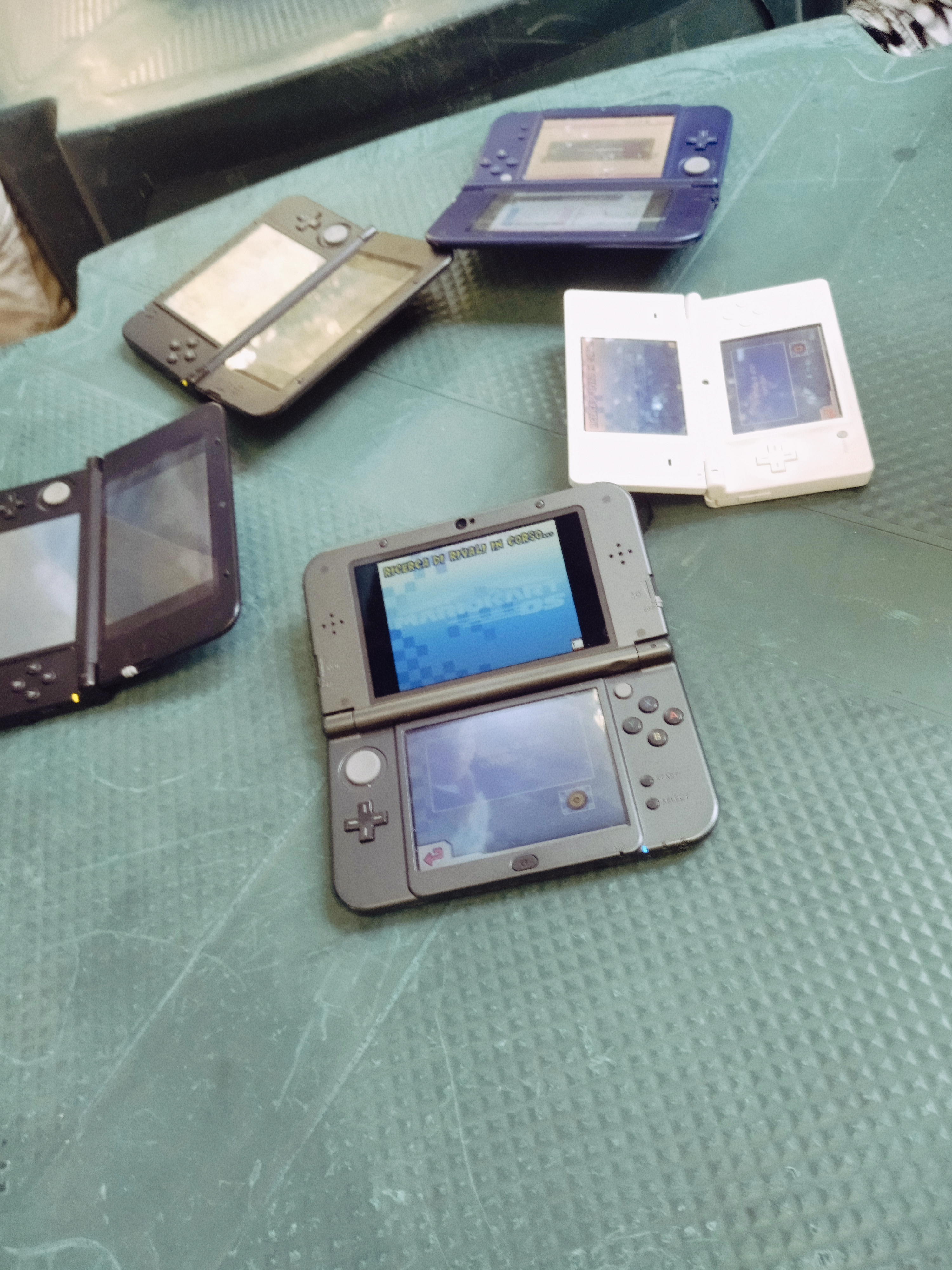 Tavolo verde all'aperto con diversi modelli di Nintendo DS, nel tentativo di giocare a Mario Kart DS.