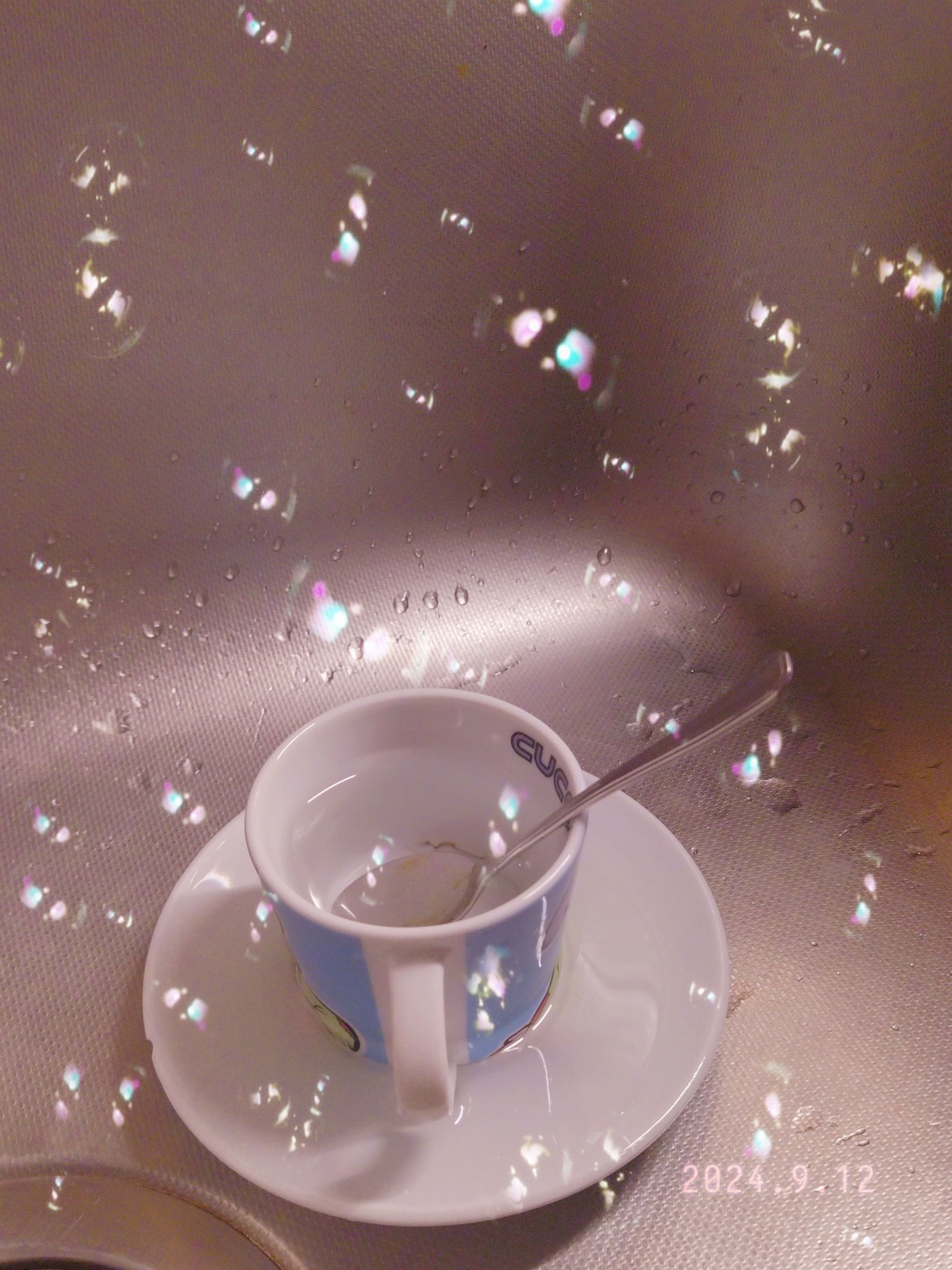 Tazzina di caffè nel lavello, riempita d'acqua, effetto filtro bolle di sapone nella foto.